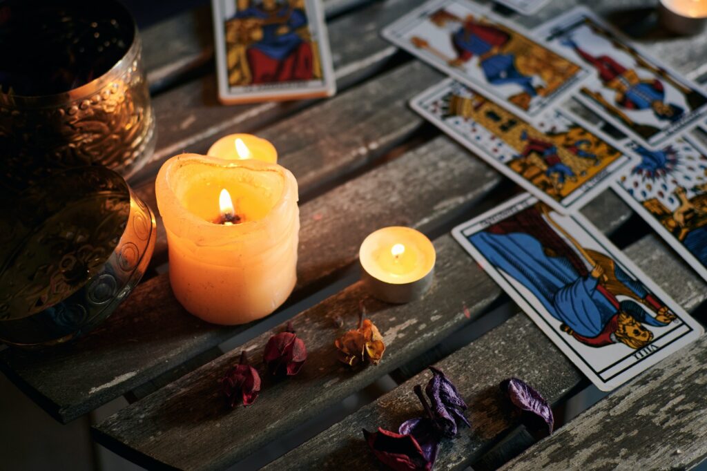 Lighted candles on a wooden table filled with tarot cards